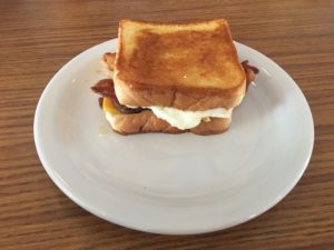 A breakfast sandwich with toast, bacon, sausage, egg, and cheese at Village Kitchen in Angola, IN