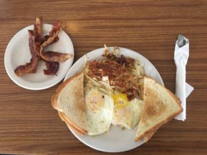 A breakfast platter with eggs, toast, bacon, and hash browns at Village Kitchen in Angola, IN