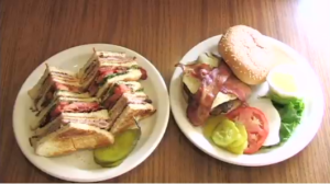 A sandwich with pickles next to a burger with bacon at Village Kitchen in Angola, IN
