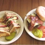 A sandwich with pickles next to a burger with bacon at Village Kitchen in Angola, IN